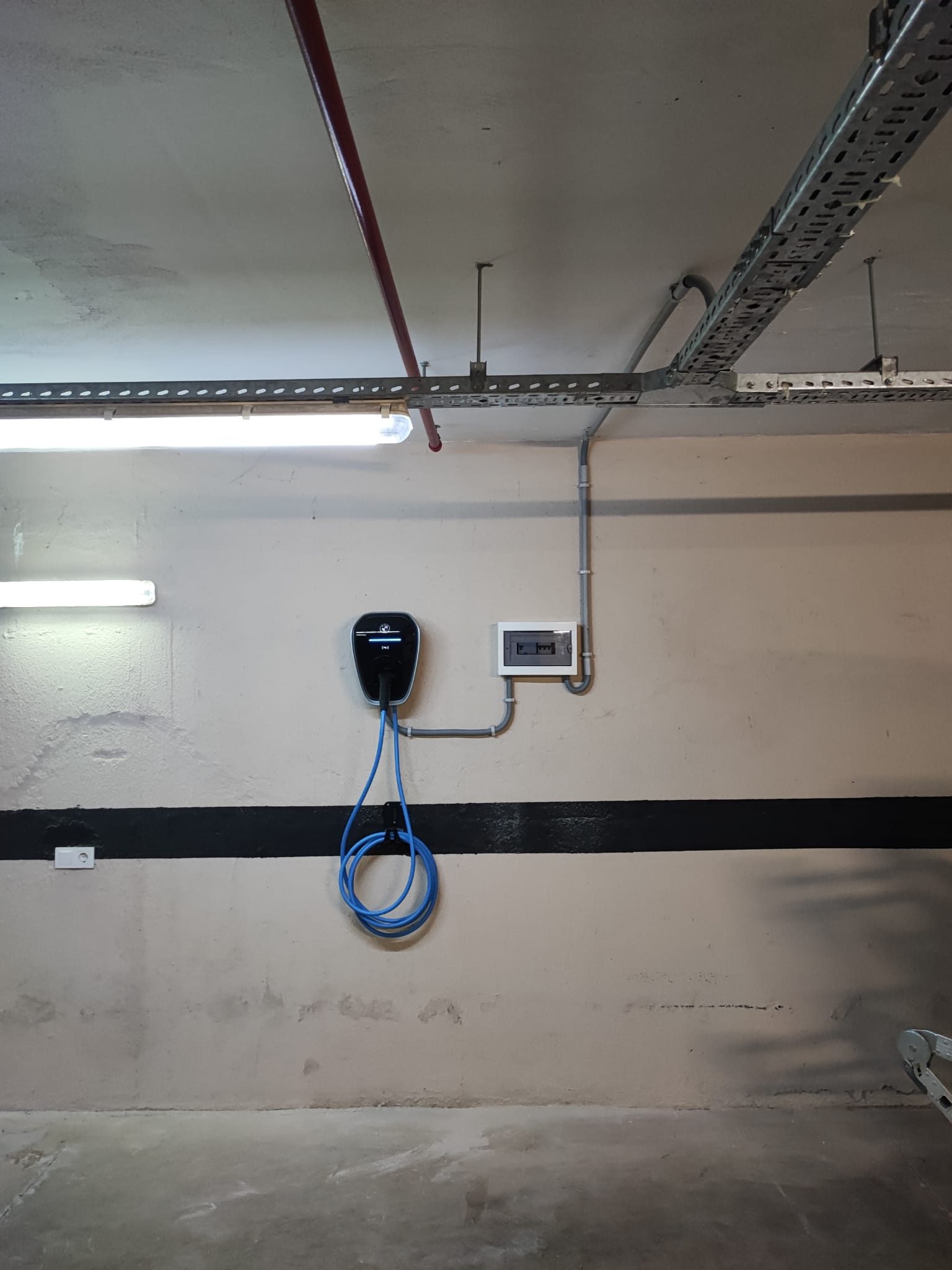 Kapalı otopark duvarında kablosu askıda tek AC şarj cihazı