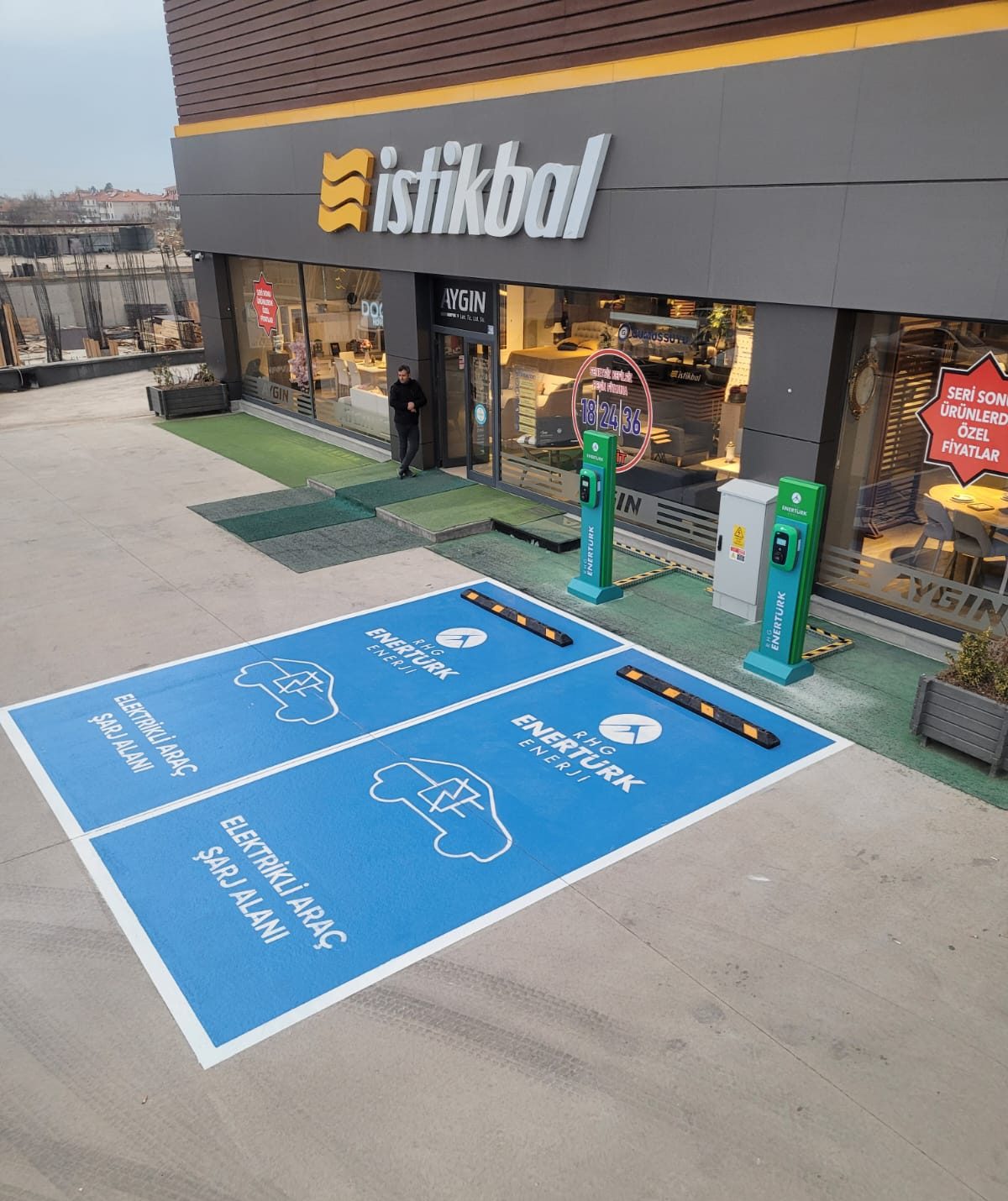 Mağaza önünde elektrikli araçlar için boyanmış park yerleri ve şarj cihazları