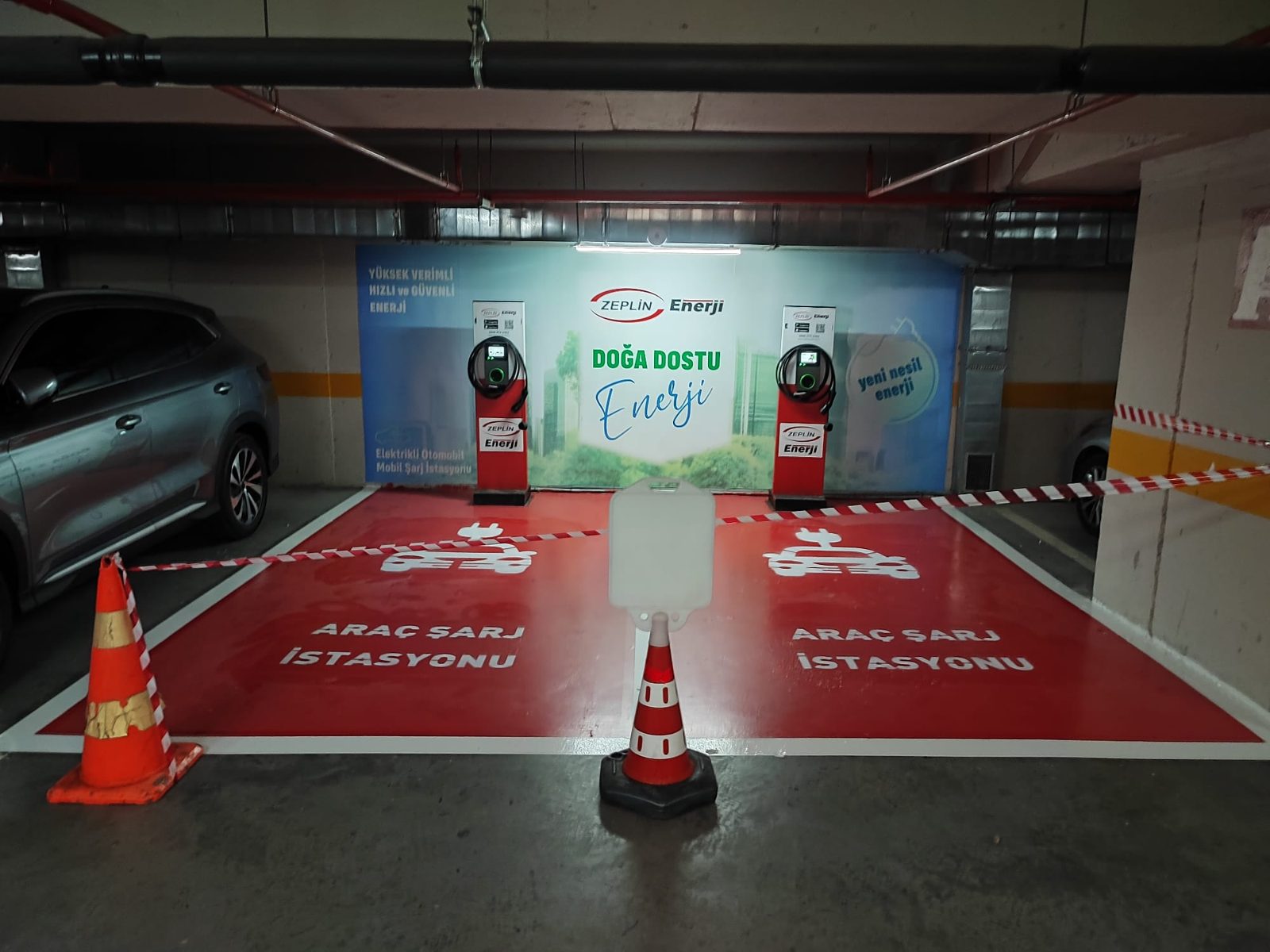 Kapalı otoparkta boyalı park alanları ve iki elektrikli araç şarj cihazı